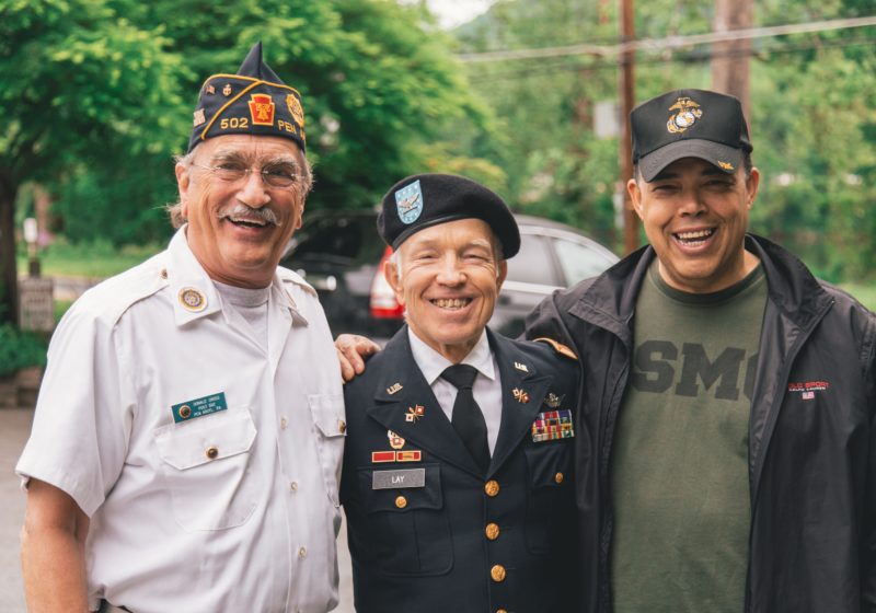 Three men in military uniforms smile.