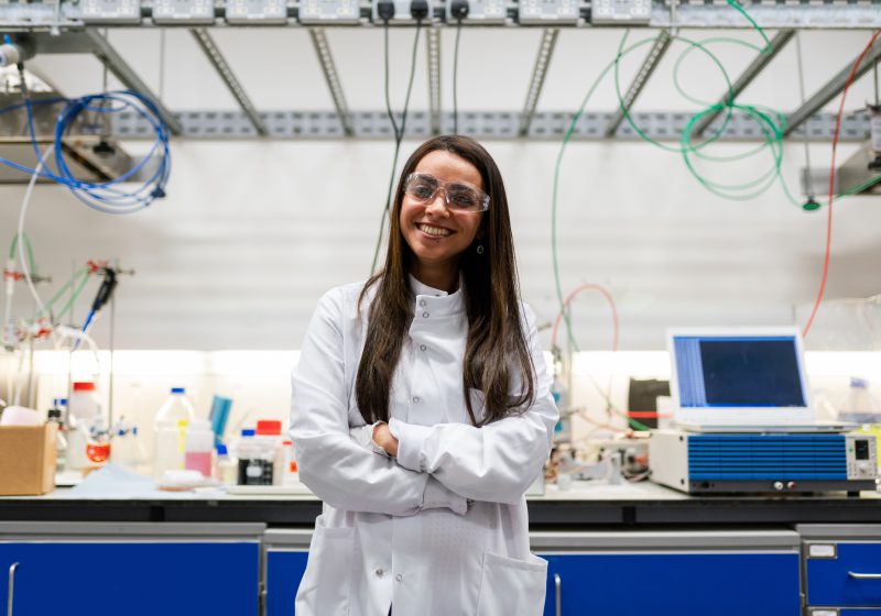 A woman in a lab coat smiling.