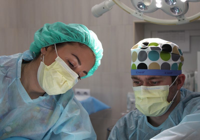Two doctors in an operating room with masks on look serious.
